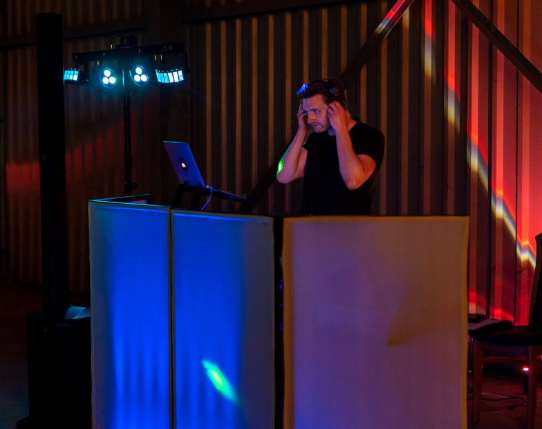 DJ Björn richtet sich die Kopfhörer beim Auflegen in Event-Location